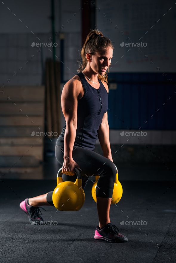 Woman athlete exercising with kettlebell by…